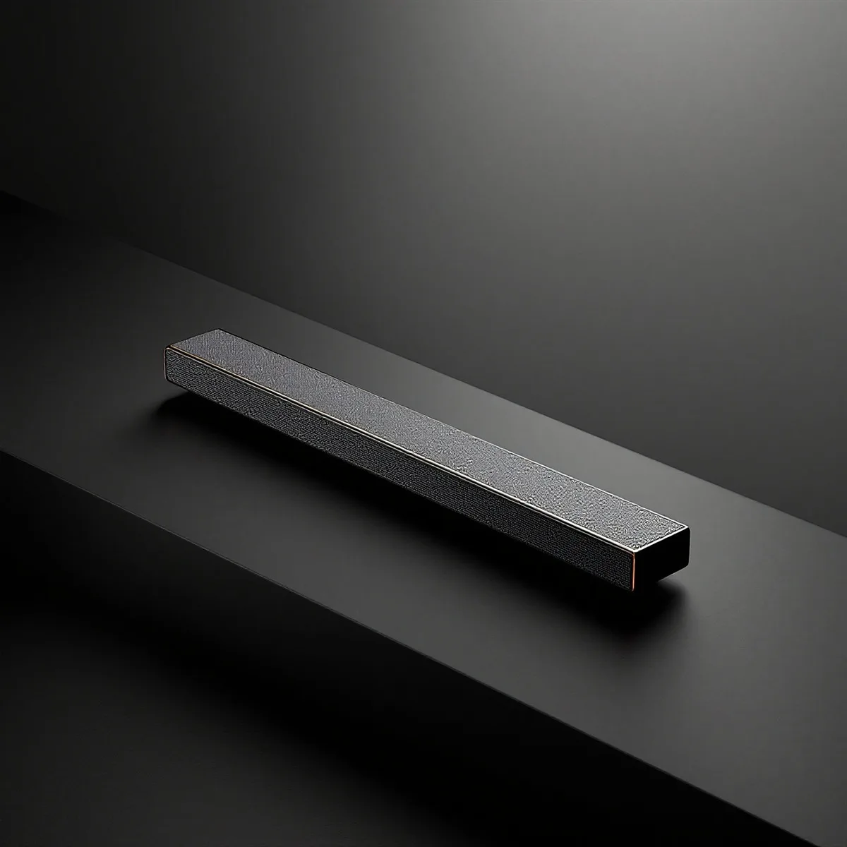 Barre de son rectangulaire noire posée sur une surface sombre.